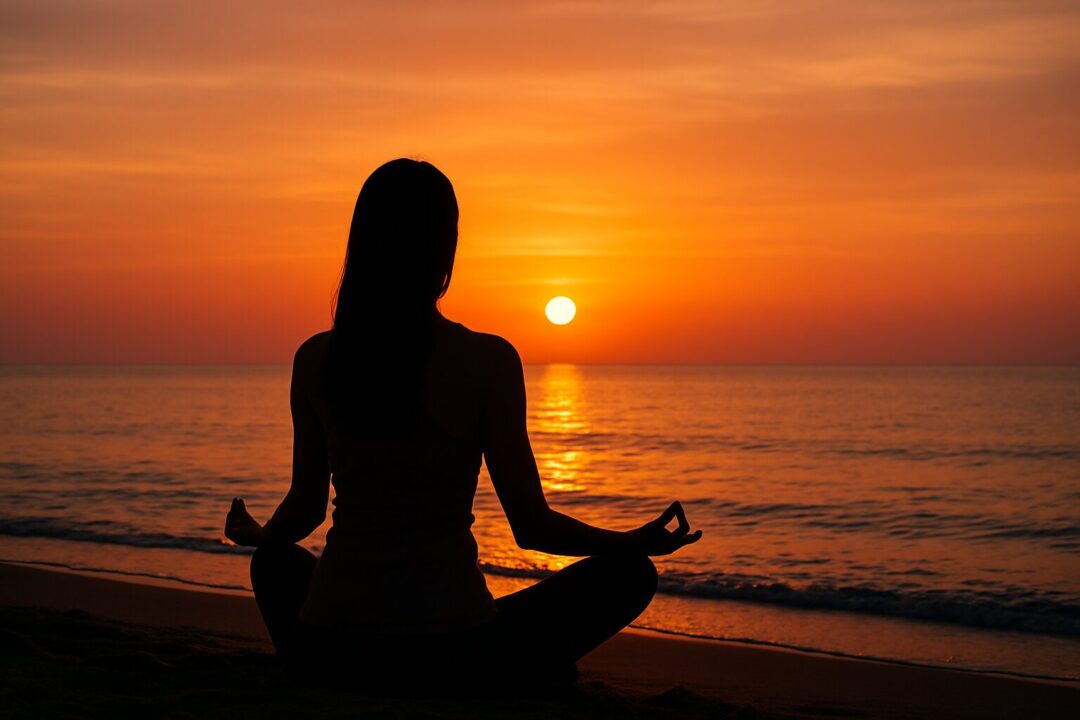 オレンジ色に染まる夕焼けの海を背景に、坐禅を組んで静かに瞑想する女性の後ろ姿。静寂と安らぎが漂う幻想的な光景。